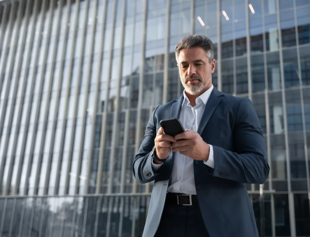 Businessman using smartphone outside modern building